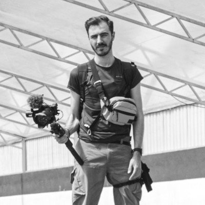 Retrato en blanco y negro de David Jaramillo con una cámara, fotógrafo publicitario